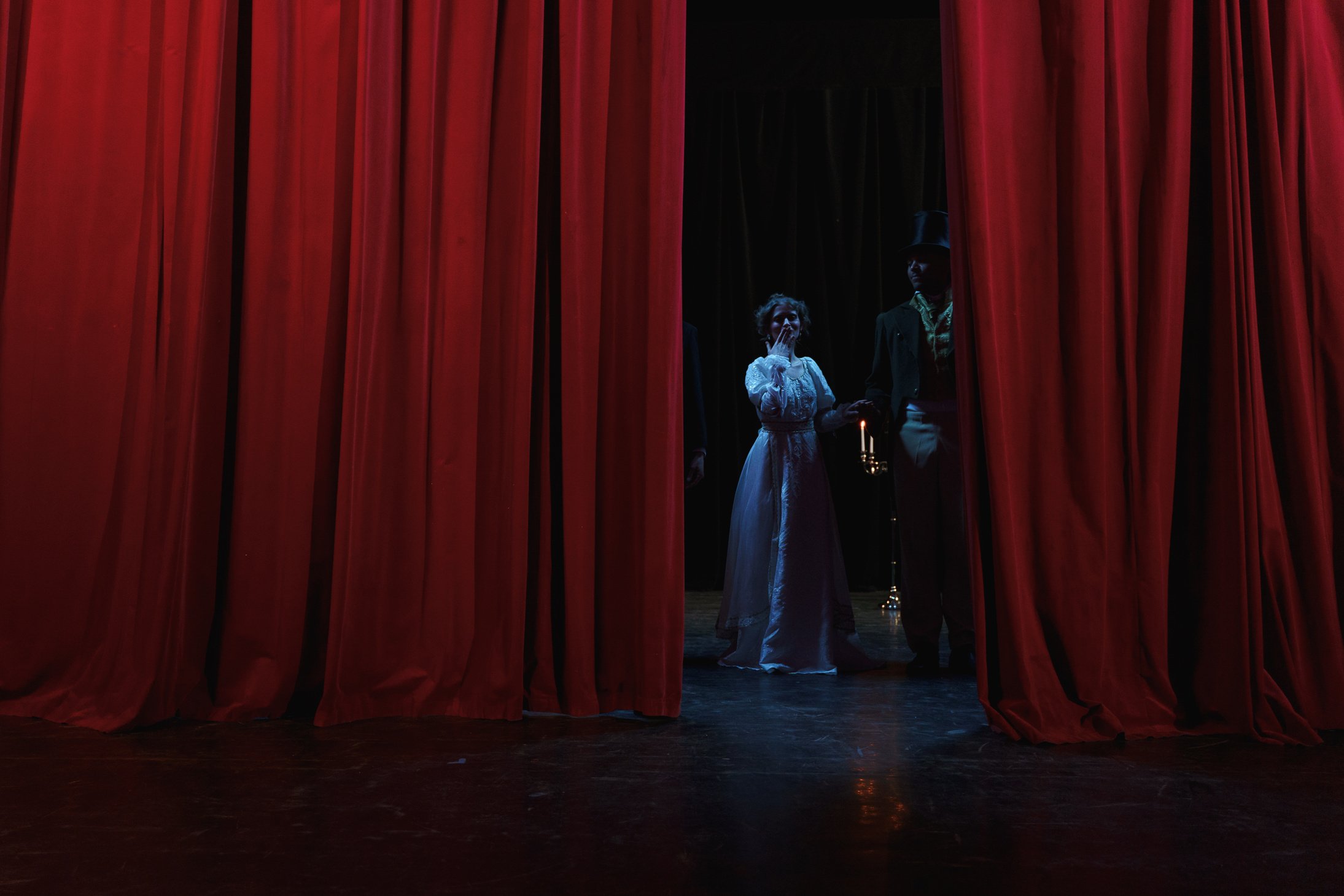 Man And Woman Standing Behind A Red Curtain